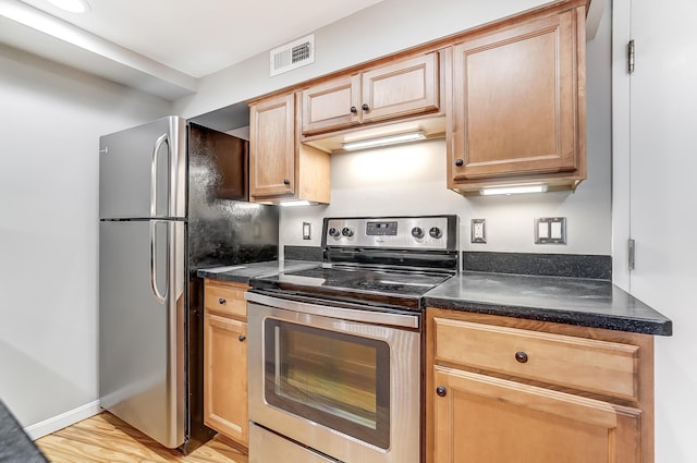 444 N Front St Unit 312, Columbus, OH 43215 - kitchen featuring appliances with stainless steel finishes, dark countertops, under cabinet range hood, and light wood-style floors