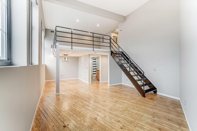 444 N Front St Unit 312, Columbus, OH 43215 - unfurnished living room featuring stairs, light wood finished floors, a towering ceiling, and recessed lighting