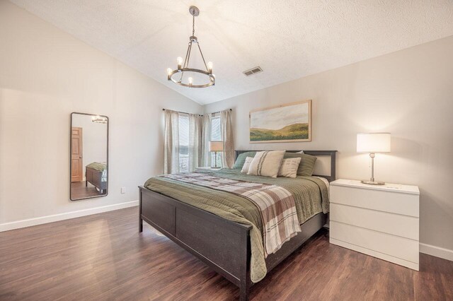 2621 Edencreek Ln, Columbus, OH 43207 - bedroom featuring a chandelier, dark wood-style flooring, vaulted ceiling, and a textured ceiling