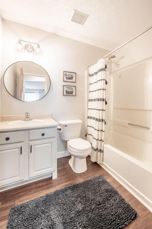 2621 Edencreek Ln, Columbus, OH 43207 - full bathroom featuring vanity, shower / tub combo with curtain, wood finished floors, and a textured ceiling