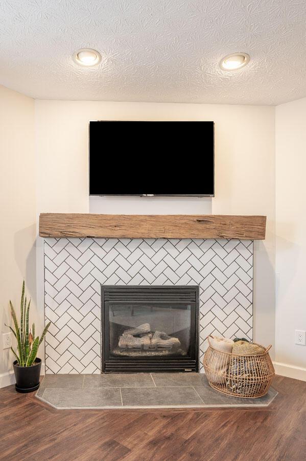 2621 Edencreek Ln, Columbus, OH 43207 - detailed view of a glass covered fireplace, wood finished floors, a textured ceiling, and recessed lighting