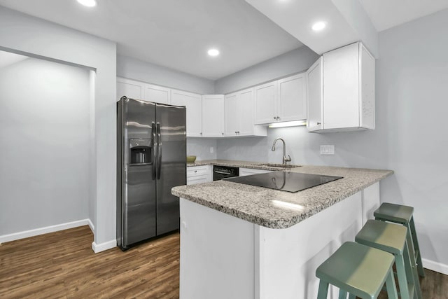 1533 Sandringham Ct, Columbus, OH 43220 - kitchen with black appliances, a peninsula, a breakfast bar, white cabinetry, and dark wood-style flooring