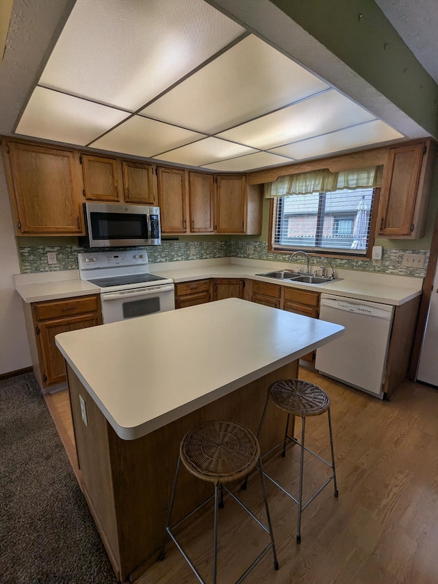 5813 Thada Ln, Columbus, OH 43229 - kitchen featuring white appliances, light countertops, brown cabinetry, backsplash, and a center island