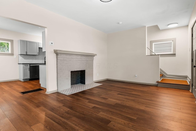 139 S Princeton Ave, Columbus, OH 43222 - unfurnished living room featuring dark wood-style flooring, stairway, and a brick fireplace