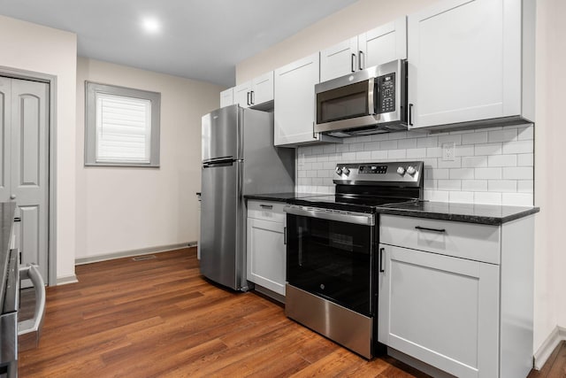 139 S Princeton Ave, Columbus, OH 43222 - kitchen featuring appliances with stainless steel finishes, tasteful backsplash, dark wood finished floors, dark stone countertops, and white cabinets