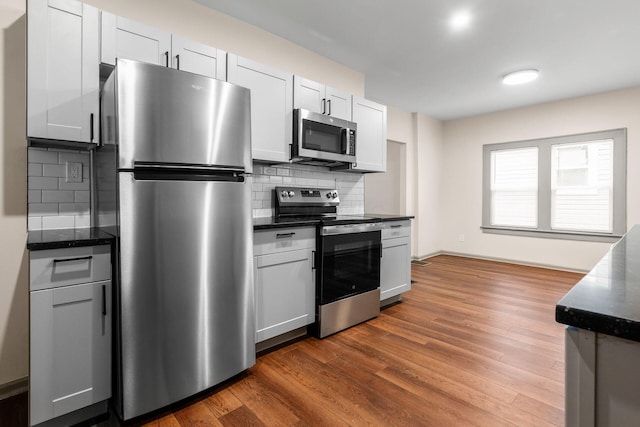139 S Princeton Ave, Columbus, OH 43222 - kitchen featuring stainless steel appliances, decorative backsplash, dark wood-type flooring, and dark stone counters