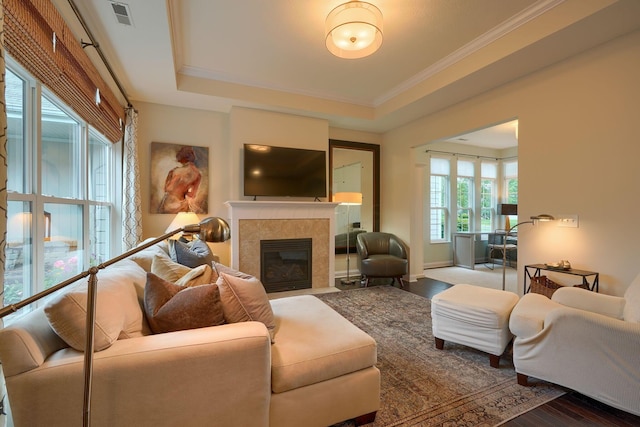 6918 Rothwell St, New Albany, OH 43054 - living room with a tile fireplace, wood finished floors, a tray ceiling, and crown molding