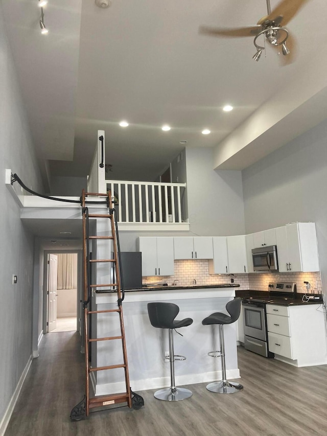 1276 N High St Unit 206, Columbus, OH 43201 - kitchen with stainless steel appliances, a high ceiling, dark wood finished floors, a breakfast bar area, and white cabinetry