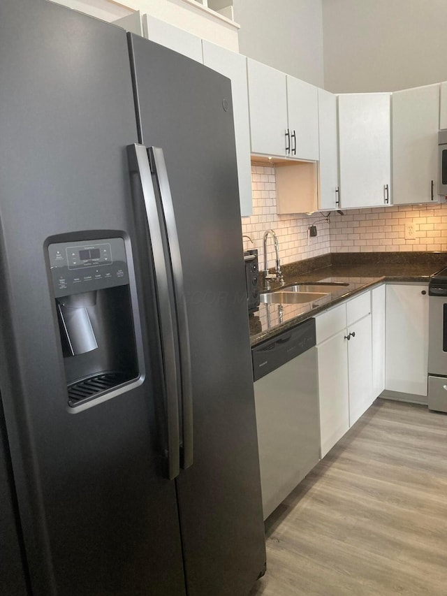 1276 N High St Unit 206, Columbus, OH 43201 - kitchen with appliances with stainless steel finishes, decorative backsplash, light wood-style floors, white cabinetry, and dark stone counters