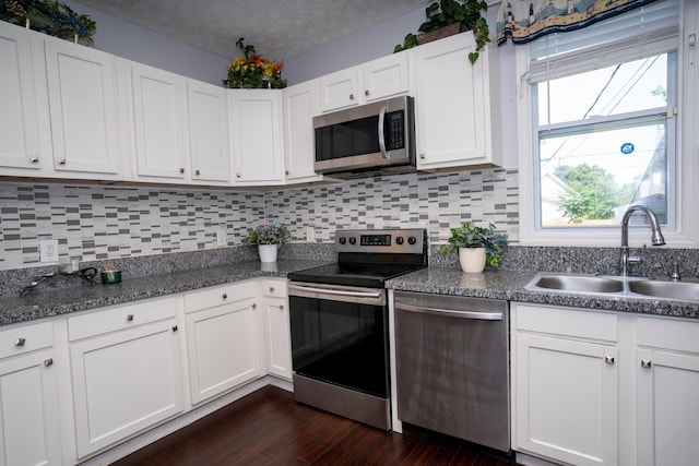 66 S Wheatland Ave, Columbus, OH 43204 - kitchen with stainless steel appliances, backsplash, white cabinets, dark wood finished floors, and a textured ceiling