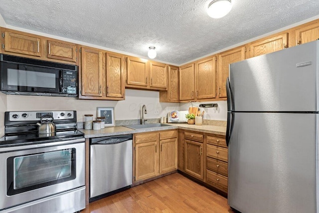 3155 El Greco Dr, Columbus, OH 43204 - kitchen featuring appliances with stainless steel finishes, light countertops, light wood-style floors, and a textured ceiling