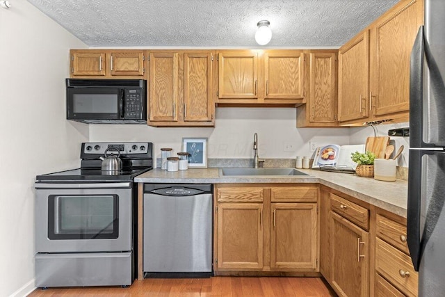 3155 El Greco Dr, Columbus, OH 43204 - kitchen featuring appliances with stainless steel finishes, a textured ceiling, light wood-type flooring, and light countertops