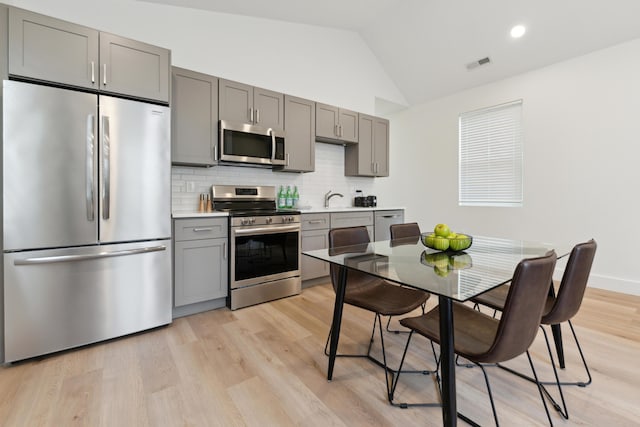 875 Bellows Ave, Columbus, OH 43223 - kitchen featuring stainless steel appliances, gray cabinets, tasteful backsplash, light countertops, and light wood-type flooring