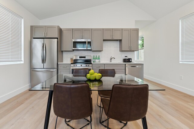 875 Bellows Ave, Columbus, OH 43223 - kitchen with appliances with stainless steel finishes, gray cabinetry, lofted ceiling, decorative backsplash, and light wood-style floors
