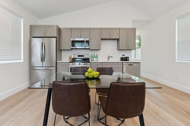 57 N Wheatland Ave, Columbus, OH 43204 - kitchen with appliances with stainless steel finishes, gray cabinetry, lofted ceiling, decorative backsplash, and light wood-style floors