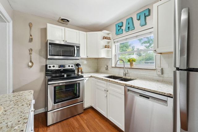 1317 Broadview Ave, Columbus, OH 43212 - kitchen featuring appliances with stainless steel finishes, white cabinetry, light wood-style floors, light stone counters, and tasteful backsplash
