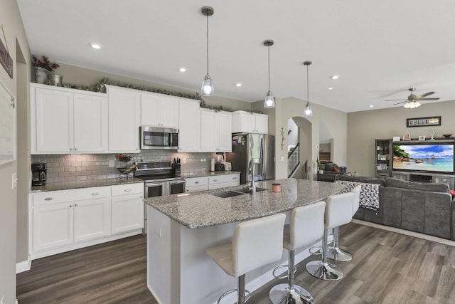7250 Konold Ct, Canal Winchester, OH 43110 - kitchen featuring appliances with stainless steel finishes, dark wood finished floors, tasteful backsplash, ceiling fan, and arched walkways
