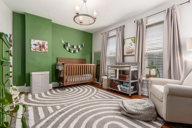 482 E Whittier St, Columbus, OH 43206 - bedroom with a chandelier, wood finished floors, multiple windows, and a nursery area