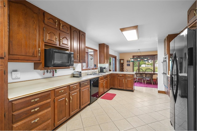 1178 London Rd, West Jefferson, OH 43162 - kitchen with black appliances, a peninsula, light tile patterned floors, light countertops, and brown cabinetry