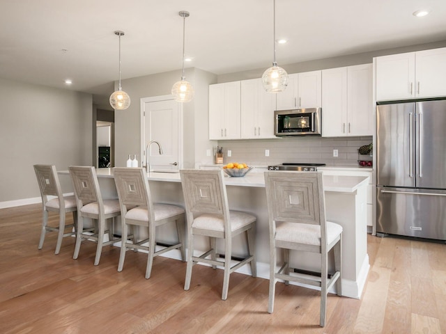 5285 Highpointe Lakes Dr Unit 201, Westerville, OH 43081 - kitchen featuring appliances with stainless steel finishes, an island with sink, light wood-type flooring, light countertops, and decorative backsplash