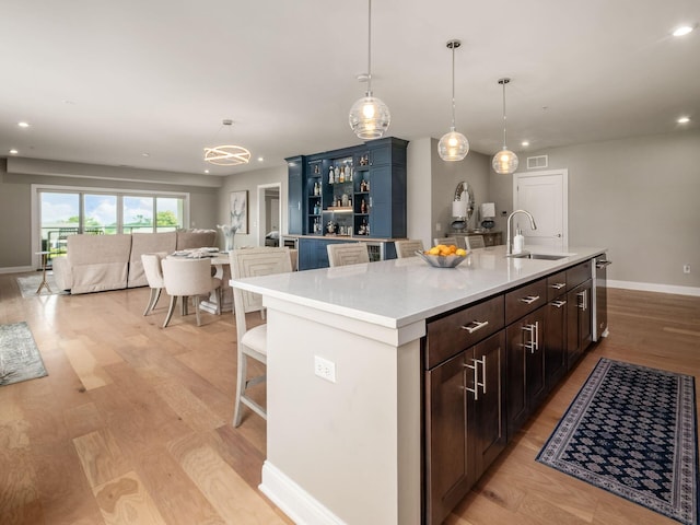 5285 Highpointe Lakes Dr Unit 201, Westerville, OH 43081 - kitchen featuring open shelves, an island with sink, light countertops, light wood-type flooring, and hanging light fixtures