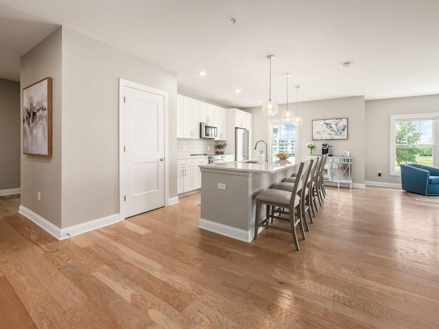 5285 Highpointe Lakes Dr Unit 201, Westerville, OH 43081 - kitchen featuring light wood-type flooring, an island with sink, stainless steel microwave, white cabinets, and recessed lighting