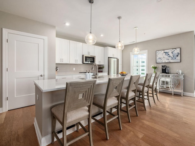 5285 Highpointe Lakes Dr Unit 201, Westerville, OH 43081 - kitchen featuring freestanding refrigerator, tasteful backsplash, light wood-style flooring, white cabinetry, and a center island with sink