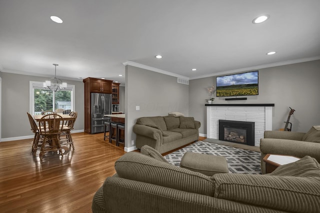 2579 Wickliffe Rd, Columbus, OH 43221 - living area with crown molding, a chandelier, recessed lighting, wood finished floors, and a brick fireplace