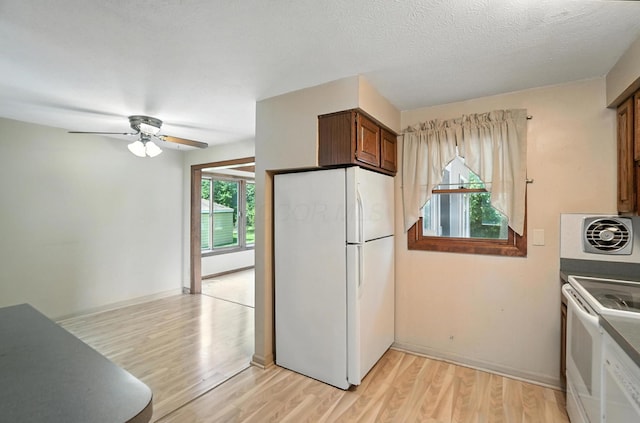 4143 Jonquil St, Columbus, OH 43224 - kitchen with white appliances, light wood-style flooring, ceiling fan, dark countertops, and brown cabinetry