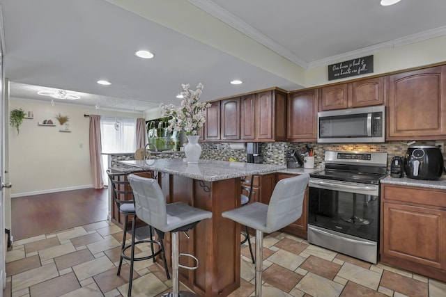 5276 Marci Way, Columbus, OH 43228 - kitchen with stainless steel appliances, ornamental molding, backsplash, a kitchen bar, and recessed lighting