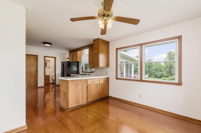 5930 Coonpath Rd NW, Carroll, OH 43112 - kitchen featuring a peninsula, wood finished floors, light countertops, a ceiling fan, and brown cabinetry