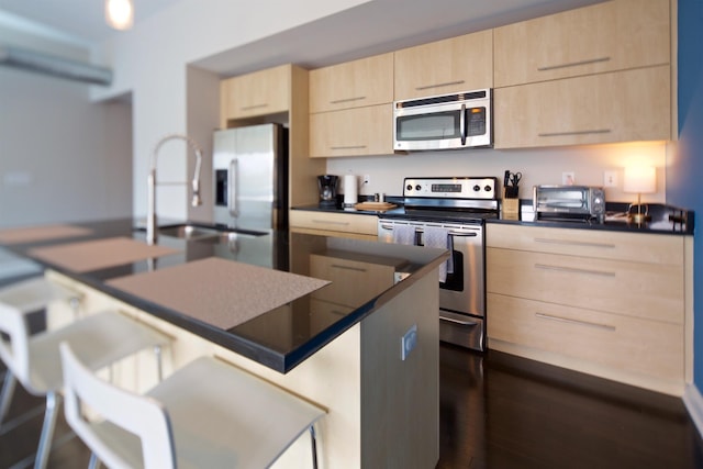100 E Gay St Unit 804, Columbus, OH 43215 - kitchen featuring appliances with stainless steel finishes, light brown cabinetry, dark countertops, and a kitchen breakfast bar