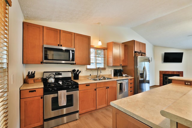 3808 Peak Ridge Dr, Columbus, OH 43230 - kitchen featuring stainless steel appliances, lofted ceiling, light wood-style floors, light countertops, and a tile fireplace