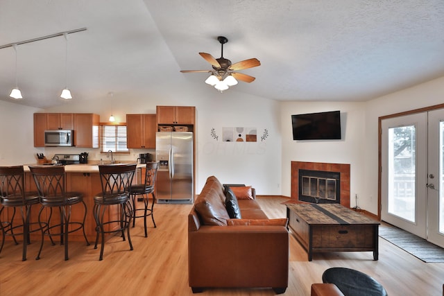 3808 Peak Ridge Dr, Columbus, OH 43230 - living area featuring lofted ceiling, light wood-style flooring, ceiling fan, a fireplace, and a textured ceiling