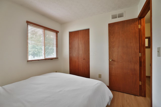 3808 Peak Ridge Dr, Columbus, OH 43230 - bedroom with a textured ceiling, light wood-style flooring, and a closet