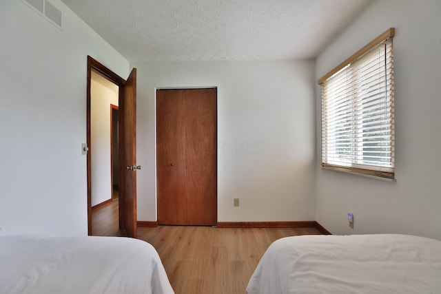 3808 Peak Ridge Dr, Columbus, OH 43230 - bedroom with light wood-style floors, a textured ceiling, and a closet