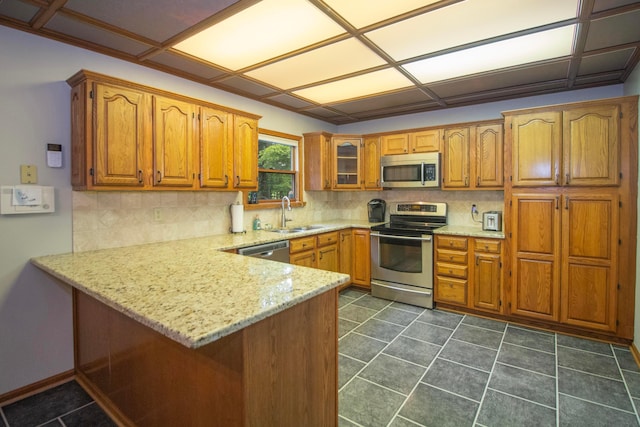 7740 Gale Rd SW, Hebron, OH 43025 - kitchen with stainless steel appliances, a peninsula, brown cabinetry, and decorative backsplash