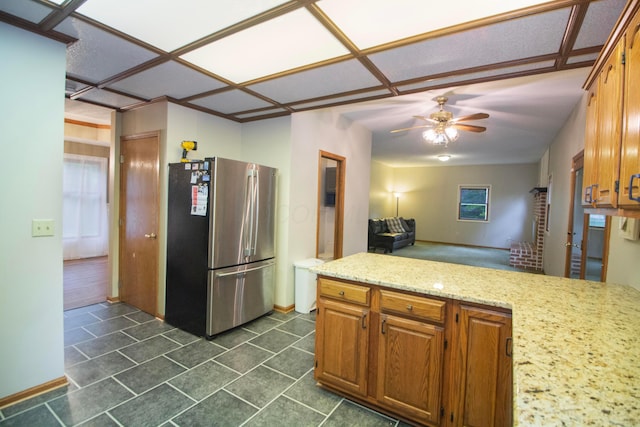 7740 Gale Rd SW, Hebron, OH 43025 - kitchen with freestanding refrigerator, ceiling fan, brown cabinets, light stone countertops, and a peninsula