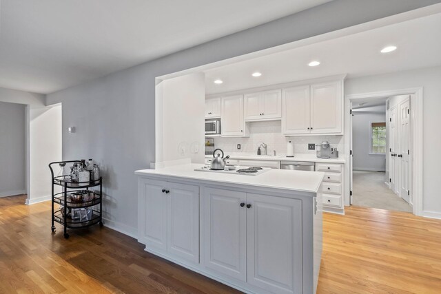 2560 Zollinger Rd, Columbus, OH 43221 - kitchen with stainless steel appliances, white cabinetry, light countertops, a peninsula, and light wood finished floors