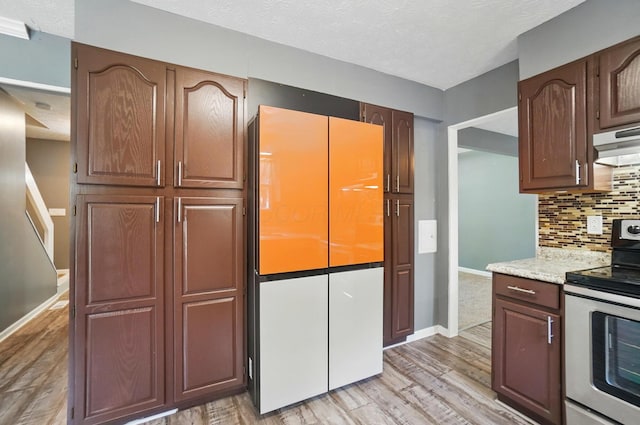 2605 Bella Via Ave, Columbus, OH 43231 - kitchen featuring stainless steel range with electric cooktop, light wood-style flooring, decorative backsplash, under cabinet range hood, and a textured ceiling