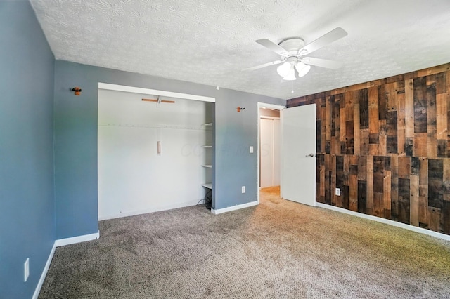 2605 Bella Via Ave, Columbus, OH 43231 - unfurnished bedroom with carpet flooring, a textured ceiling, a closet, wood walls, and ceiling fan