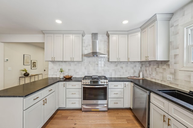 527 N Columbia Ave, Bexley, OH 43209 - kitchen with wall chimney exhaust hood, stainless steel appliances, a peninsula, decorative backsplash, and dark countertops