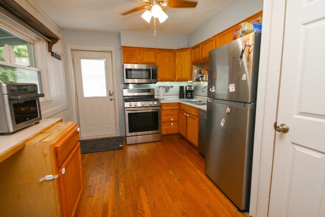 1810 Lehner Rd, Columbus, OH 43224 - kitchen with appliances with stainless steel finishes, dark wood-type flooring, a ceiling fan, light countertops, and brown cabinets