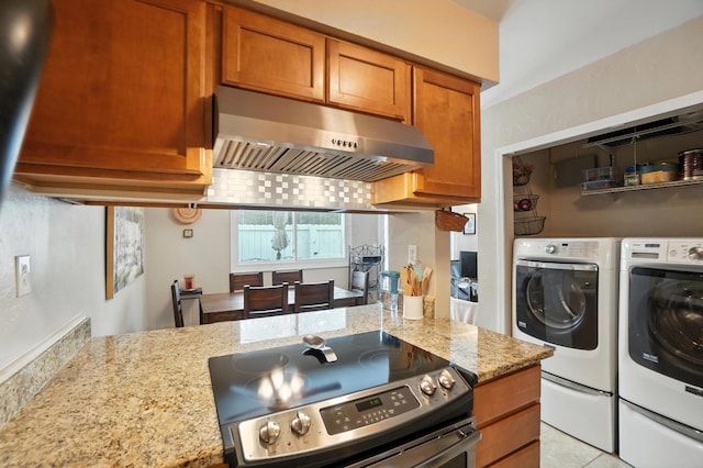 3063 Jersey Dr Unit 67, Columbus, OH 43204 - kitchen featuring under cabinet range hood, stainless steel range with electric stovetop, washer and clothes dryer, light stone countertops, and brown cabinets