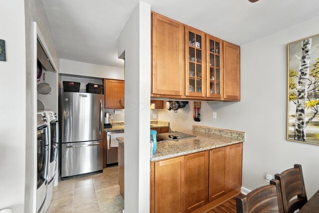 3063 Jersey Dr Unit 67, Columbus, OH 43204 - kitchen featuring stainless steel appliances, brown cabinetry, glass insert cabinets, and light stone countertops