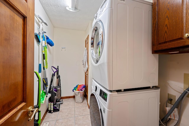175 Academy Woods Dr, Columbus, OH 43230 - laundry area featuring stacked washer / dryer, cabinet space, light tile patterned floors, and a textured ceiling