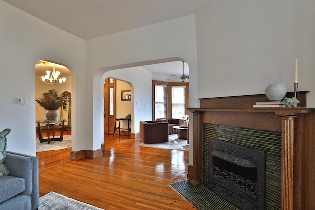 398 W 5th Ave, Columbus, OH 43201 - living area with arched walkways, a tiled fireplace, wood-type flooring, a ceiling fan, and a chandelier