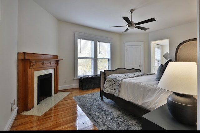 398 W 5th Ave, Columbus, OH 43201 - bedroom featuring light wood finished floors, a tiled fireplace, and a ceiling fan