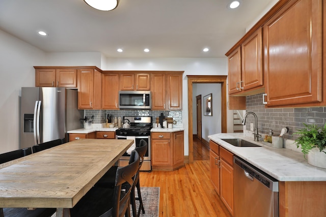 398 W 5th Ave, Columbus, OH 43201 - kitchen featuring stainless steel appliances, light wood-type flooring, brown cabinets, light countertops, and decorative backsplash