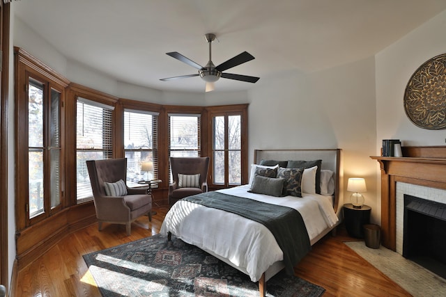 398 W 5th Ave, Columbus, OH 43201 - bedroom featuring wood finished floors, a tiled fireplace, and a ceiling fan